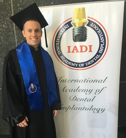 Image of Dr. Call standing next to an International Academy of Dental Implants banner, since he is a member.